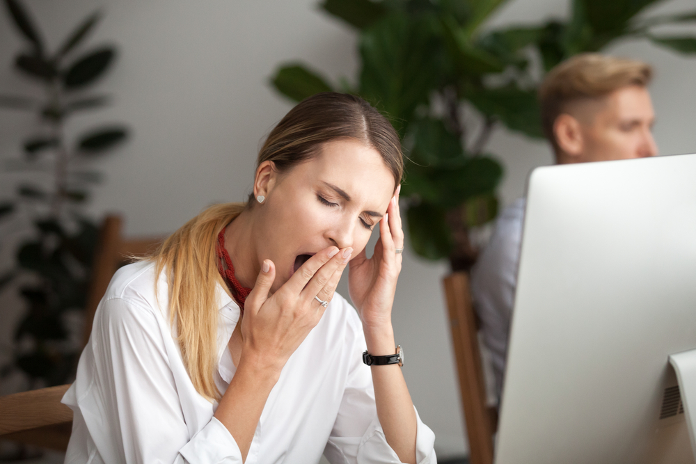 Bored tired businesswoman yawning at workplace