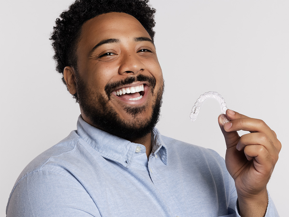 Man smiling holding clear retainer